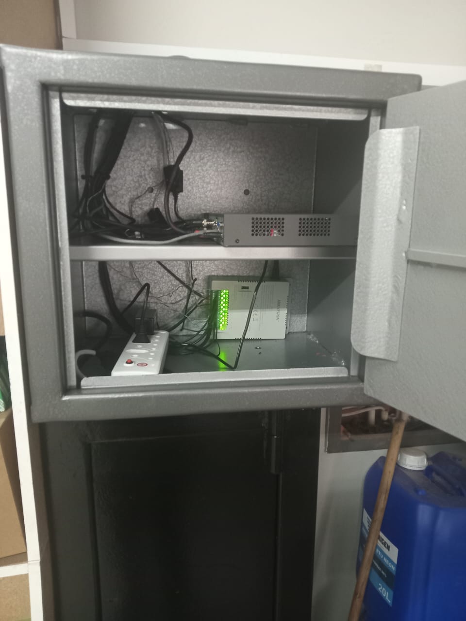 Camera recorder and network switch on shelves inside an open steel cabinet